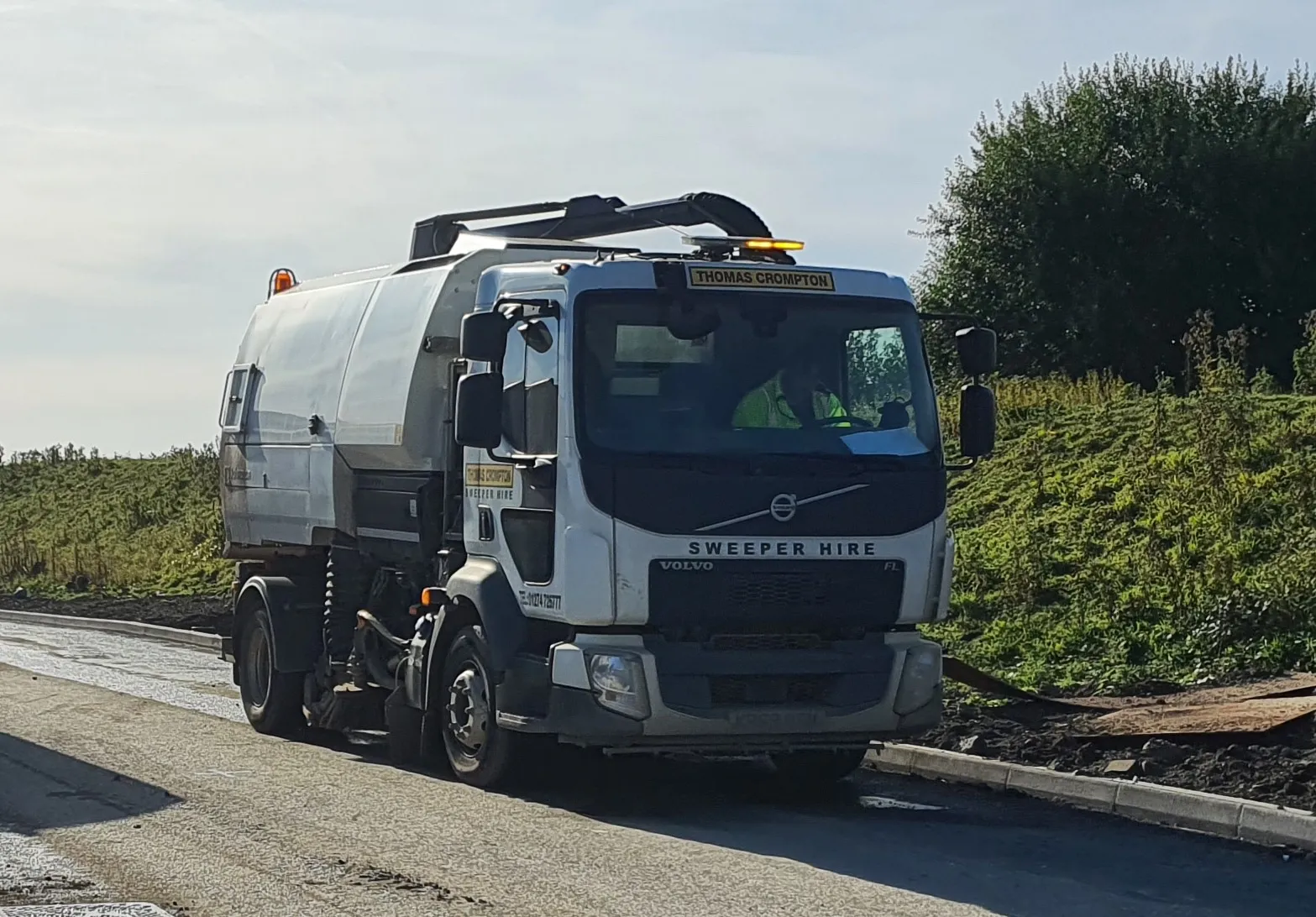 Road sweeper cleaning a busy street